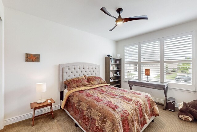 carpeted bedroom featuring baseboards and a ceiling fan