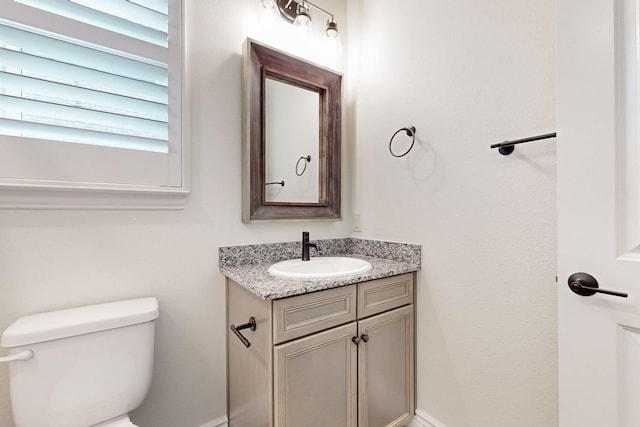 half bath featuring vanity, baseboards, and toilet