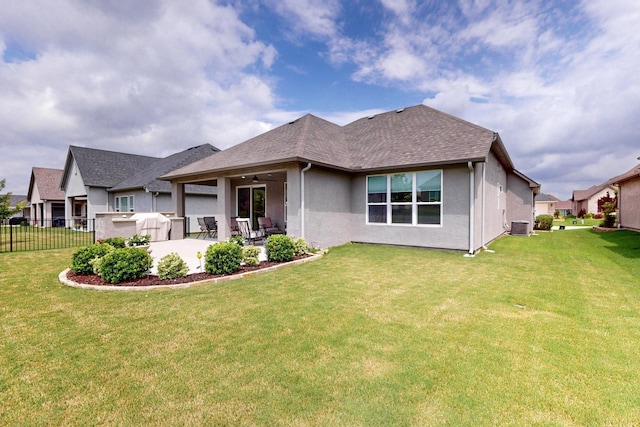 back of house with ceiling fan, fence, stucco siding, a patio area, and a lawn
