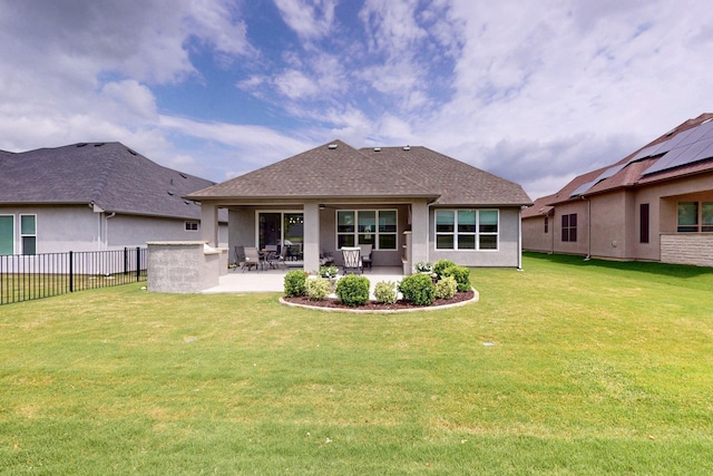 back of house with roof with shingles, a patio area, fence, a yard, and stucco siding