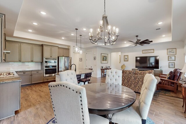 dining area featuring visible vents, recessed lighting, ceiling fan with notable chandelier, and a tray ceiling