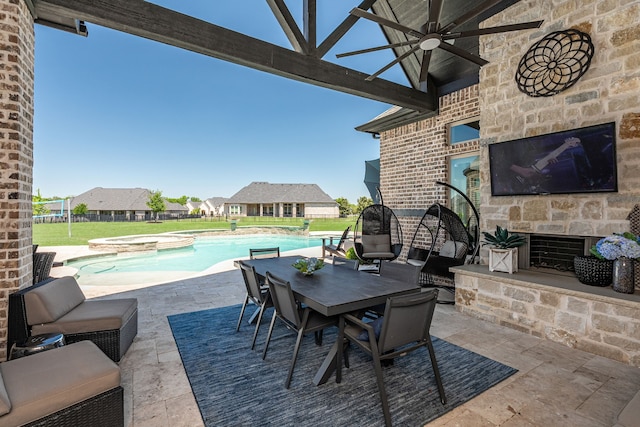 view of patio with an outdoor stone fireplace, a ceiling fan, and an outdoor pool