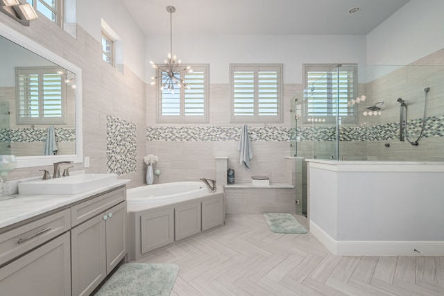 bathroom with tile walls, a shower stall, an inviting chandelier, and a wealth of natural light