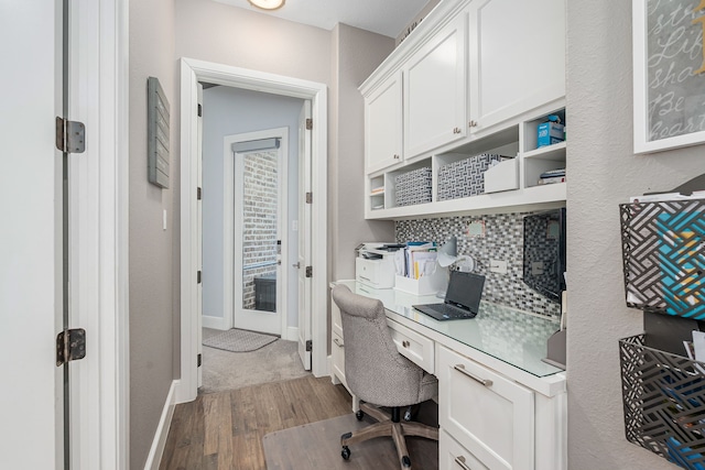 office with baseboards, built in desk, and wood finished floors