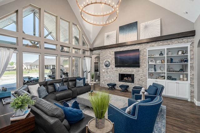 living area featuring a chandelier, high vaulted ceiling, dark wood finished floors, and a stone fireplace