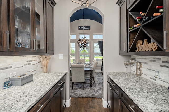 4241 Tranquility Ln, Prosper, TX 75078 - bar featuring dark wood-type flooring, tasteful backsplash, a chandelier, and arched walkways