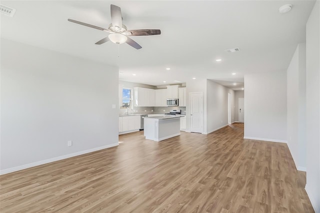 unfurnished living room featuring baseboards, a ceiling fan, and light wood-style flooring