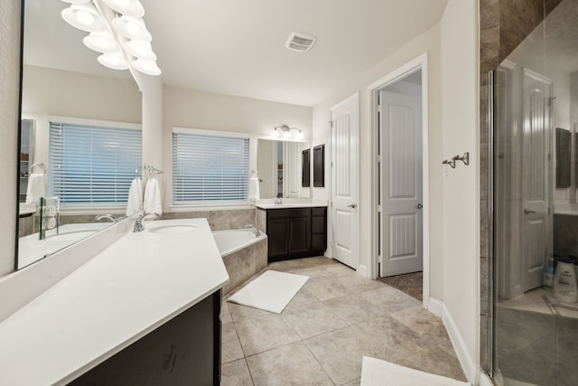 full bathroom featuring a bath, visible vents, tile patterned flooring, a stall shower, and two vanities