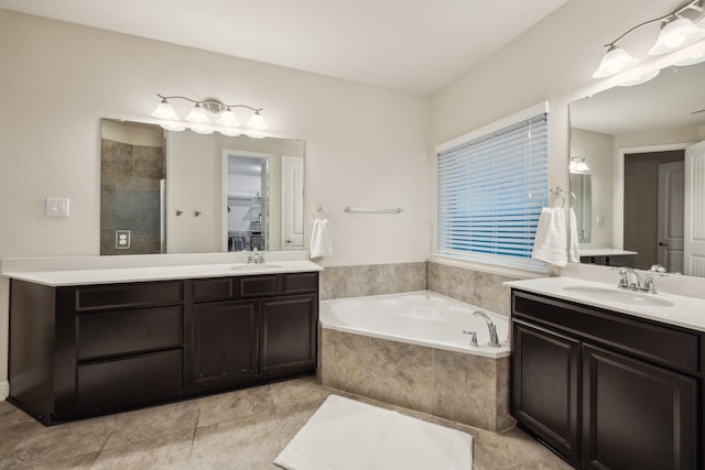 bathroom featuring a garden tub, a sink, two vanities, and a tile shower