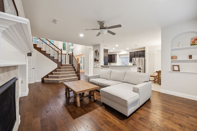 living area with ceiling fan, a fireplace, baseboards, visible vents, and dark wood-style floors