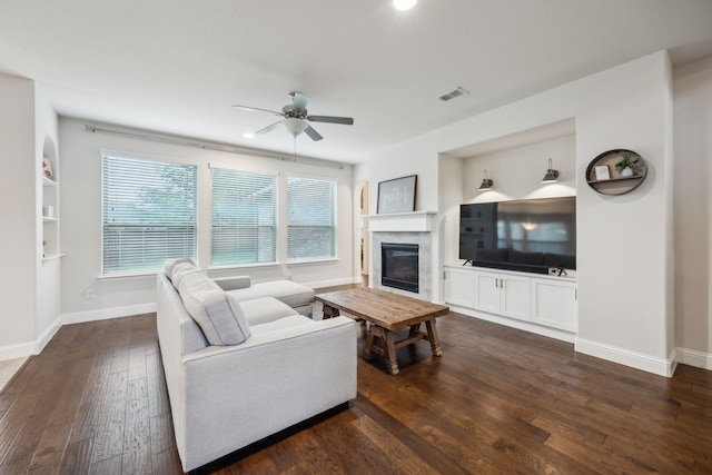 living room featuring visible vents, dark wood finished floors, a glass covered fireplace, and baseboards