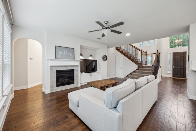 living area featuring arched walkways, dark wood-style flooring, ceiling fan, and a healthy amount of sunlight