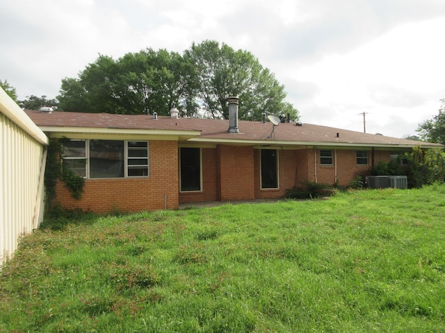 back of property featuring a lawn, brick siding, and central AC