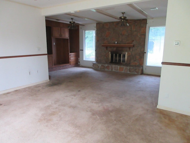 unfurnished living room with a ceiling fan, a fireplace, carpet floors, baseboards, and beamed ceiling