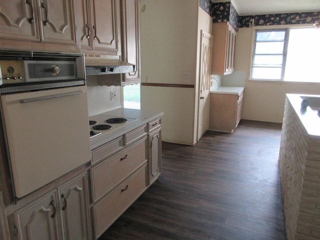 kitchen featuring light countertops, under cabinet range hood, white appliances, and dark wood-type flooring