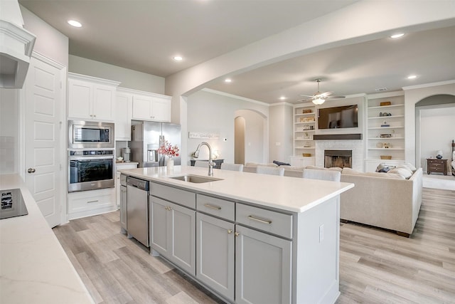 kitchen with ceiling fan, gray cabinets, arched walkways, a sink, and appliances with stainless steel finishes