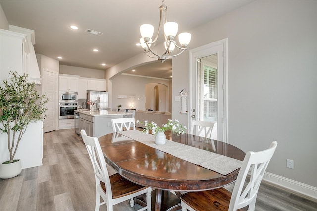 dining area with an inviting chandelier, visible vents, arched walkways, light wood-style floors, and recessed lighting