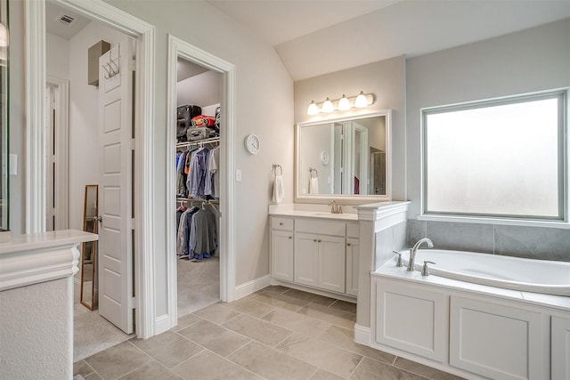full bath featuring a bath, visible vents, vanity, baseboards, and a spacious closet