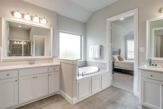 ensuite bathroom with vanity, a bath, vaulted ceiling, and a shower stall