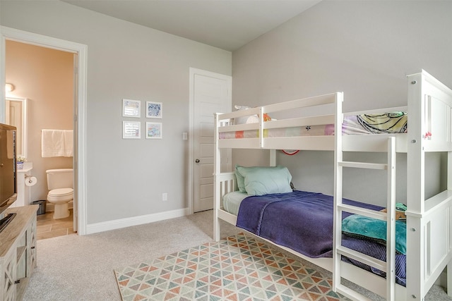 bedroom featuring baseboards, ensuite bath, and light colored carpet