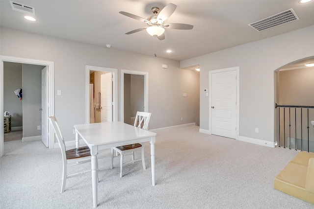 dining room with a ceiling fan, arched walkways, visible vents, and light carpet