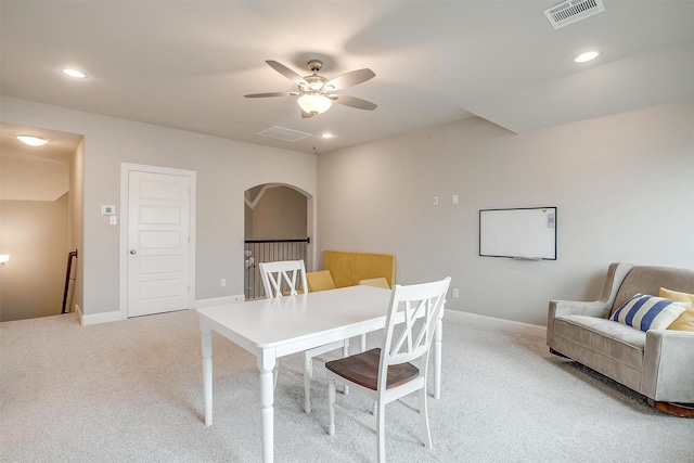 office area featuring light colored carpet, ceiling fan, visible vents, and arched walkways