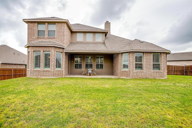 back of property with a fenced backyard, a chimney, a lawn, and brick siding
