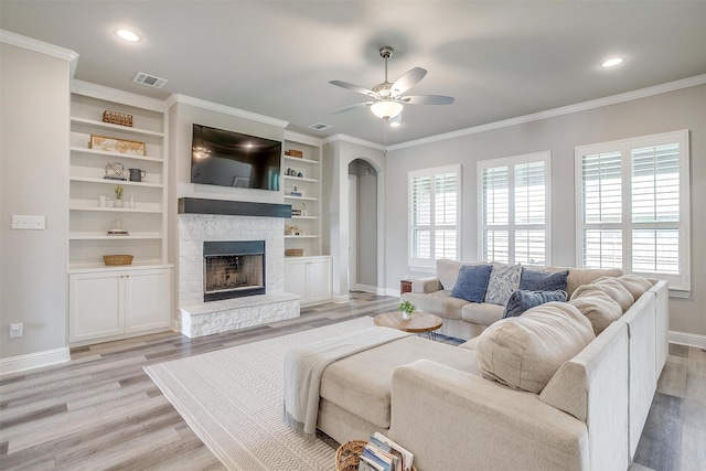 living area with visible vents, a fireplace, baseboards, light wood-type flooring, and a ceiling fan