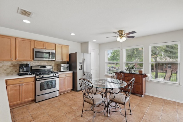 kitchen with light countertops, stainless steel appliances, a ceiling fan, backsplash, and visible vents
