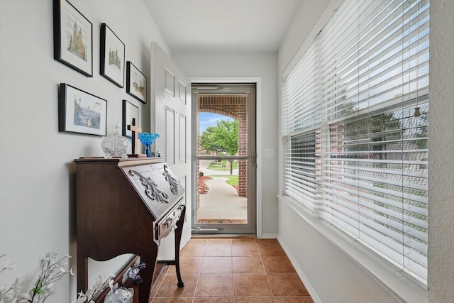 doorway to outside with tile patterned flooring and baseboards