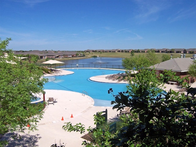 community pool featuring a water view, fence, and a residential view