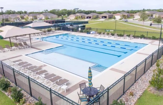 community pool with a patio, fence, and a residential view