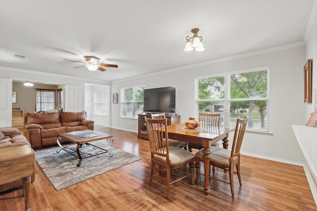 dining room featuring crown molding, a ceiling fan, baseboards, light wood-type flooring, and visible vents