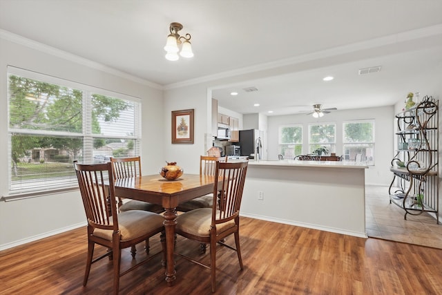 dining space with crown molding, baseboards, light wood-type flooring, and visible vents