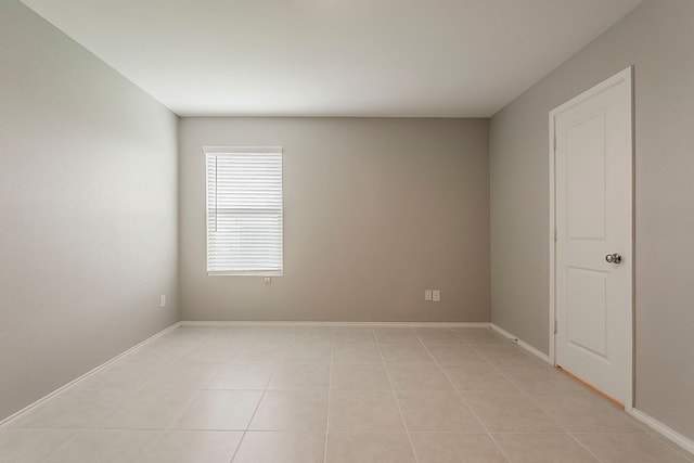 spare room featuring light tile patterned floors and baseboards