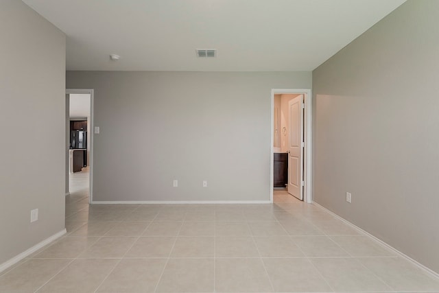 empty room with visible vents, baseboards, and light tile patterned floors
