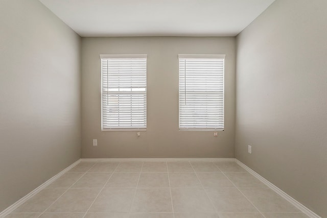 unfurnished room with baseboards, light tile patterned flooring, and a wealth of natural light