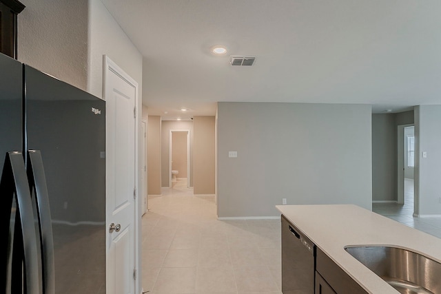 kitchen featuring light tile patterned flooring, light countertops, freestanding refrigerator, stainless steel dishwasher, and visible vents