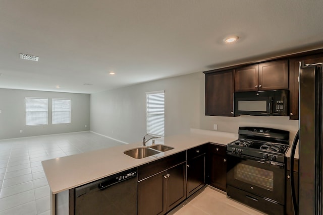 kitchen featuring a sink, light tile patterned floors, black appliances, a peninsula, and open floor plan