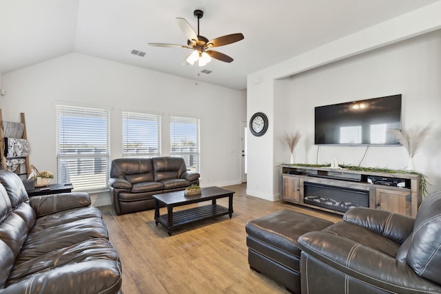 living room featuring vaulted ceiling, a ceiling fan, light wood finished floors, and visible vents