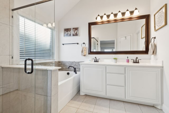 full bathroom with tile patterned flooring, vaulted ceiling, a sink, and a garden tub