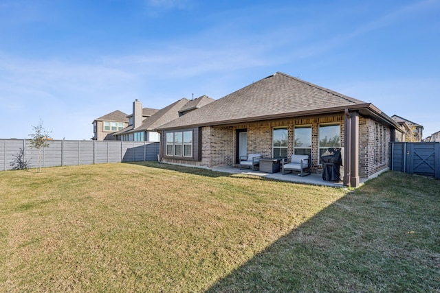 rear view of house featuring a fenced backyard, a yard, and brick siding