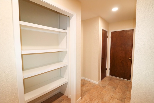 corridor featuring a textured wall and recessed lighting