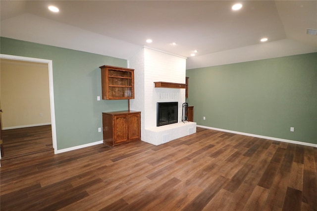 unfurnished living room with a brick fireplace, dark wood-style flooring, baseboards, vaulted ceiling, and recessed lighting