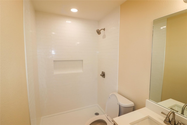 full bath featuring vanity, toilet, tiled shower, and recessed lighting