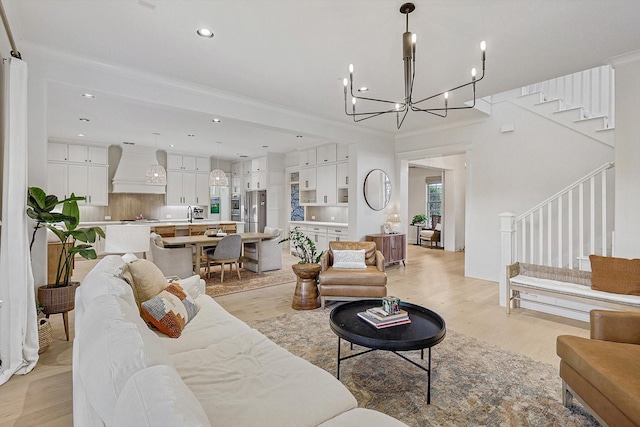living area with an inviting chandelier, stairway, recessed lighting, and light wood-style flooring