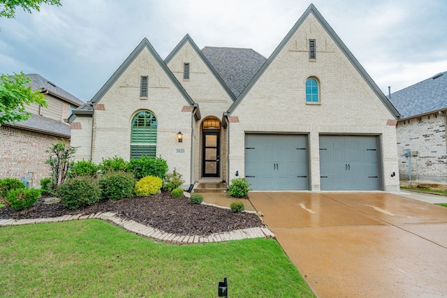 view of front facade with a front yard, brick siding, concrete driveway, an attached garage, and a shingled roof