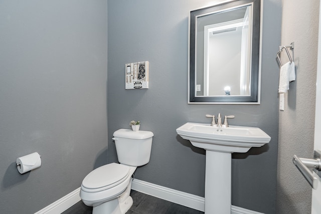 half bath featuring visible vents, baseboards, wood finished floors, and toilet
