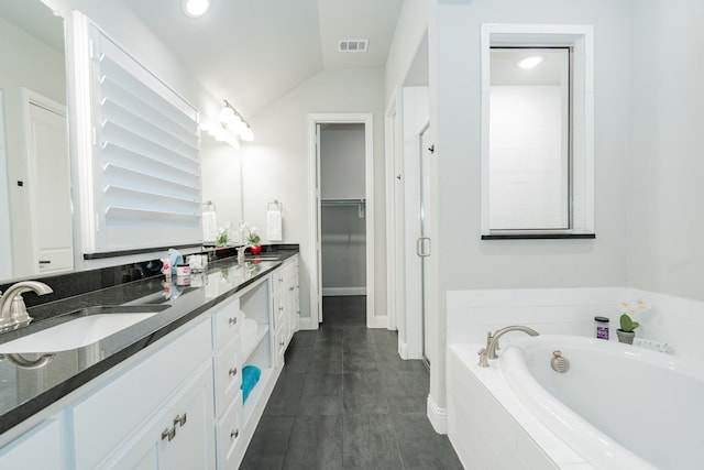 full bath with double vanity, a garden tub, visible vents, vaulted ceiling, and a sink