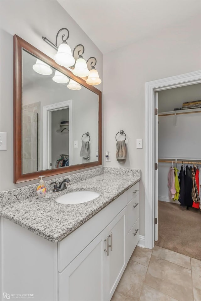 bathroom with tile patterned floors, a spacious closet, and vanity